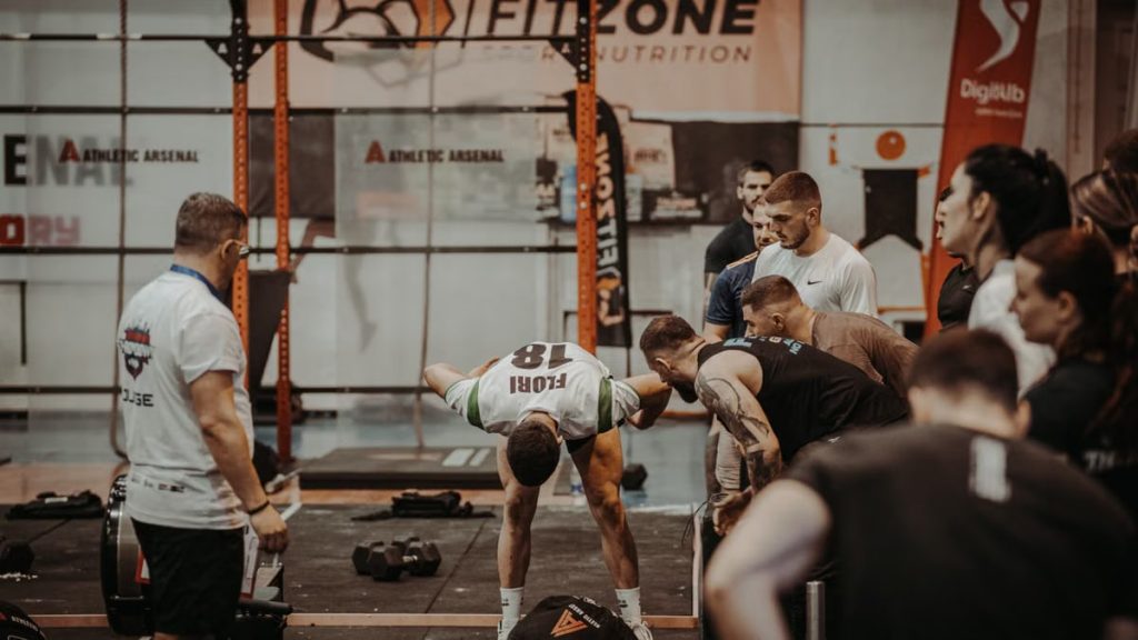 Group of athletes engaging in a competitive CrossFit workout at a gym with emphasis on strength and teamwork.